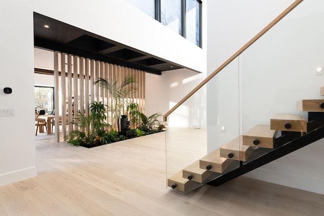 stairway featuring wood finished floors, a towering ceiling, and baseboards