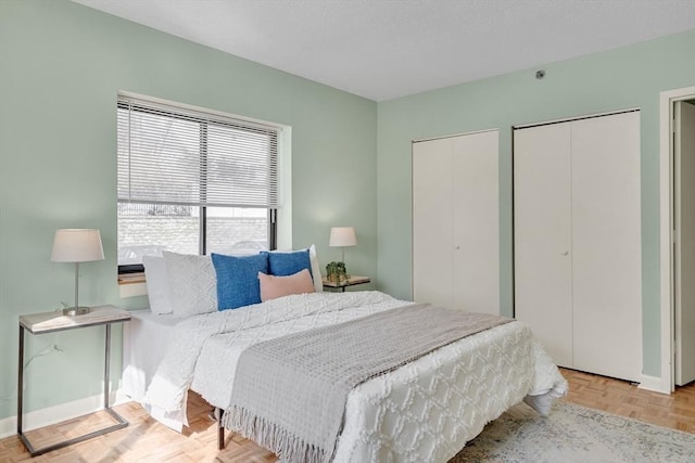 bedroom featuring baseboards and two closets