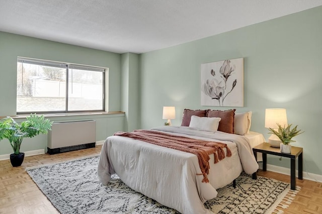 bedroom with radiator heating unit, baseboards, and a textured ceiling