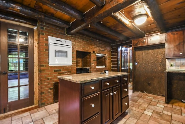 135 Pine St, Rochester, MA 02770 - kitchen featuring a wood ceiling with exposed beams, stone tile floors, dark brown cabinetry, light stone countertops, and a kitchen island