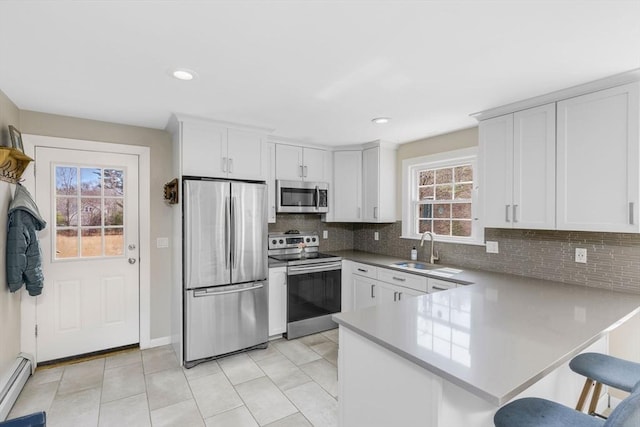 331 Townsend Rd, Groton, MA 01450 - kitchen with stainless steel appliances, a baseboard heating unit, a peninsula, backsplash, and a kitchen breakfast bar