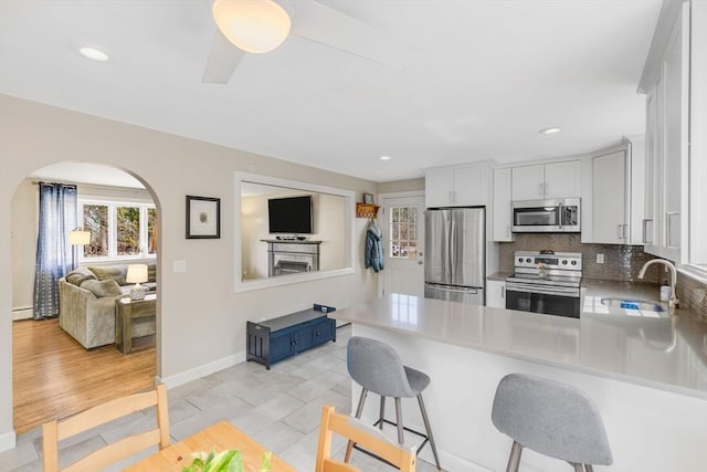 331 Townsend Rd, Groton, MA 01450 - kitchen with stainless steel appliances, a peninsula, arched walkways, backsplash, and a baseboard heating unit