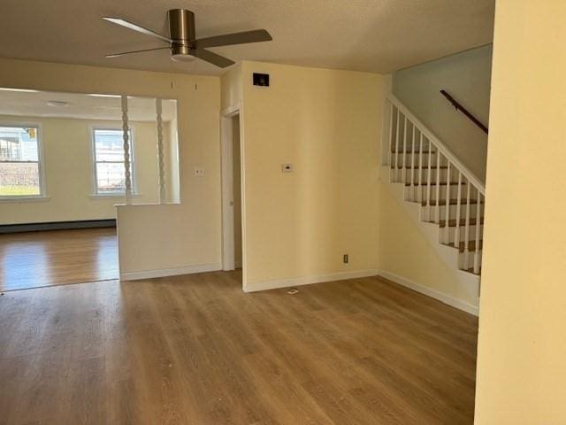 61 Belleville Rd, New Bedford, MA 02745 - unfurnished living room featuring baseboard heating, baseboards, wood finished floors, a ceiling fan, and stairs