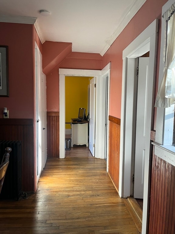 hallway featuring radiator, hardwood / wood-style flooring, and ornamental molding