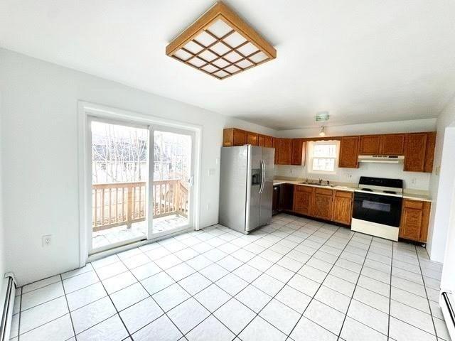 kitchen featuring electric stove, under cabinet range hood, stainless steel fridge, light countertops, and baseboard heating