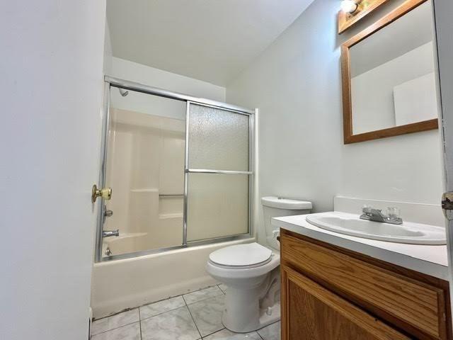 full bath with vanity, toilet, combined bath / shower with glass door, and tile patterned flooring