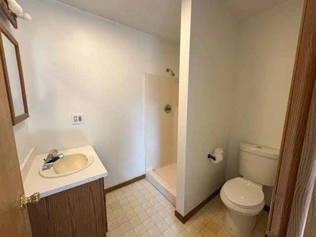 full bathroom with tile patterned floors, toilet, a shower stall, baseboards, and vanity