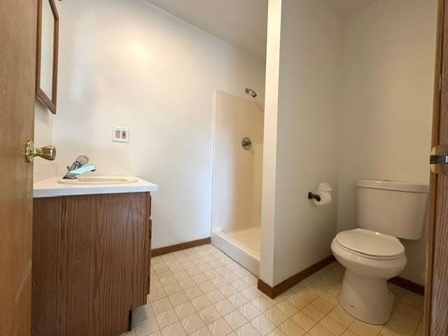 full bathroom featuring vanity, toilet, baseboards, and a stall shower