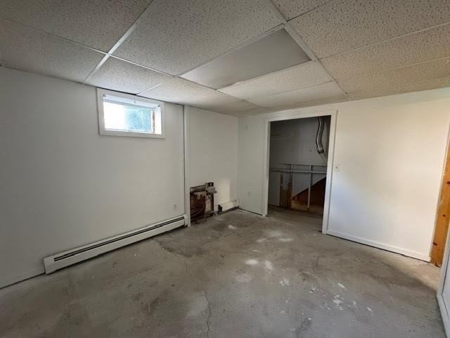 basement with a drop ceiling and a baseboard radiator