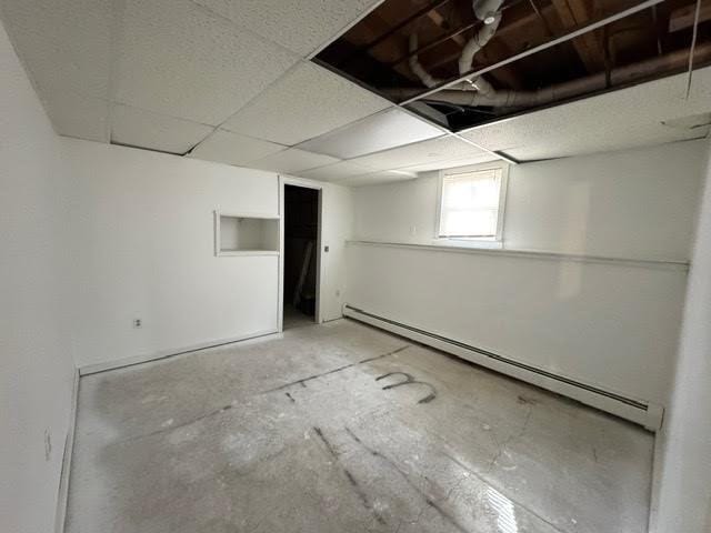 below grade area featuring a baseboard heating unit and a paneled ceiling