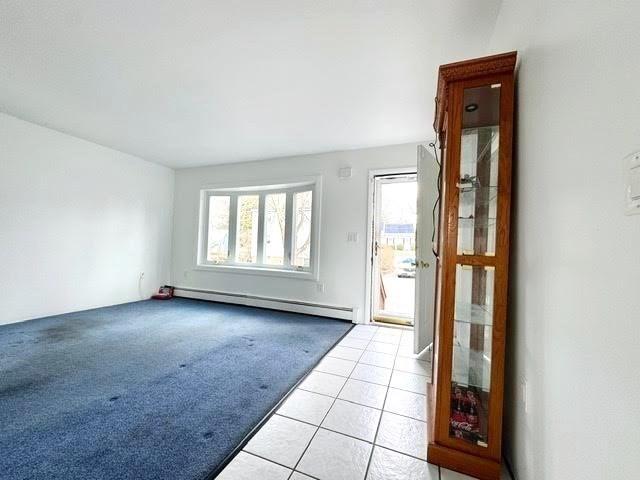 foyer with light carpet, baseboard heating, and light tile patterned flooring