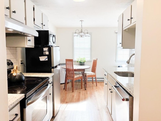 110 W Main St Unit 30, Barnstable, MA 02601 - kitchen featuring stainless steel appliances, under cabinet range hood, a sink, light wood-style flooring, and a chandelier
