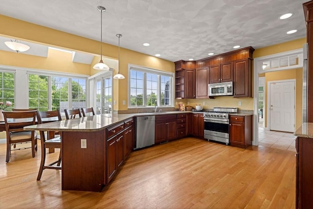 160 Wharton Row, Groton, MA 01450 - kitchen with stainless steel appliances, a kitchen bar, open shelves, a peninsula, and light wood-style floors