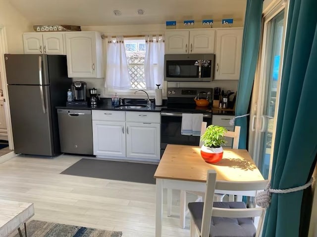 kitchen with white cabinetry, sink, appliances with stainless steel finishes, and light hardwood / wood-style flooring