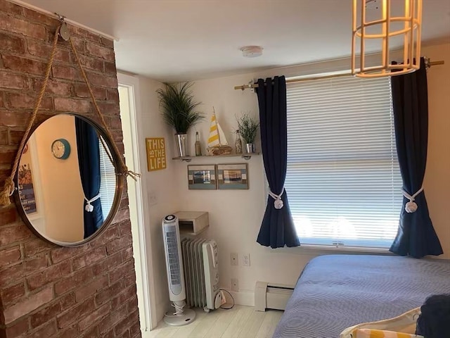 bedroom with a baseboard heating unit and brick wall