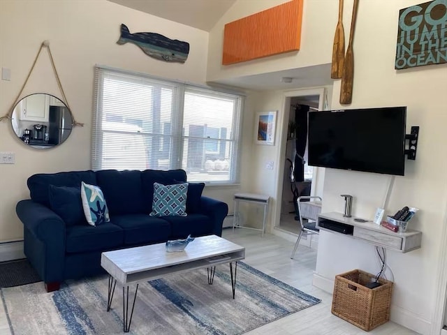 living room with hardwood / wood-style flooring, vaulted ceiling, and a baseboard heating unit