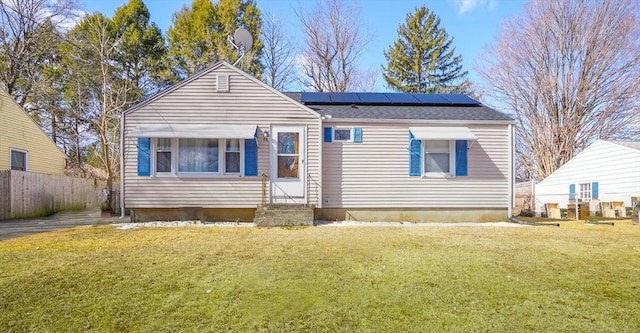 view of front of property featuring solar panels, entry steps, a front yard, and fence