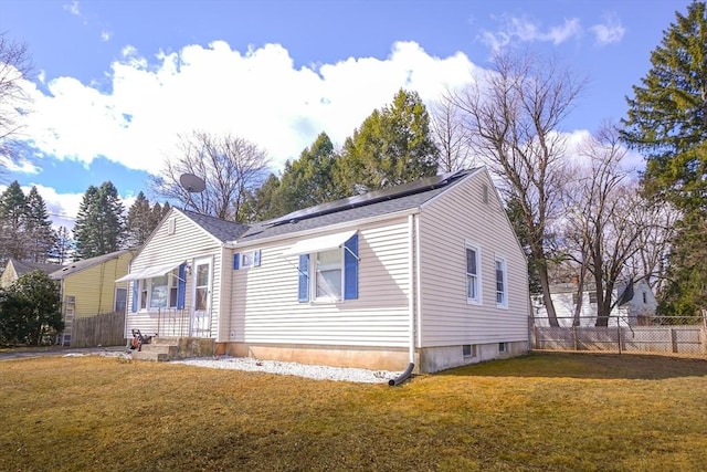 view of front of house with roof mounted solar panels, a front lawn, and fence