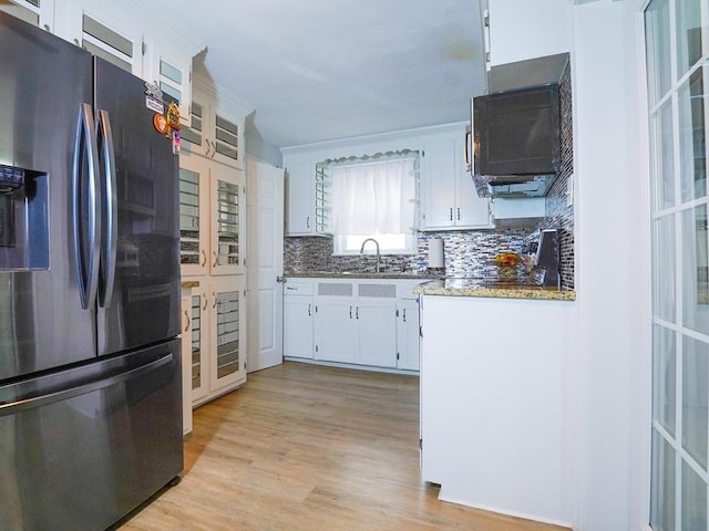 kitchen featuring decorative backsplash, light wood-style floors, stainless steel refrigerator with ice dispenser, white cabinetry, and a sink