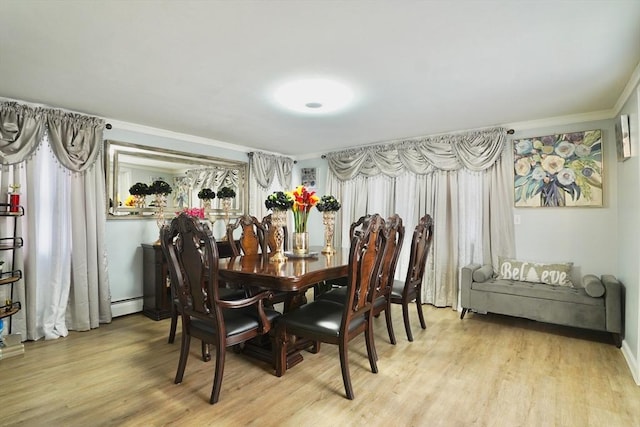 dining area featuring a baseboard heating unit, light wood-style flooring, baseboards, and ornamental molding