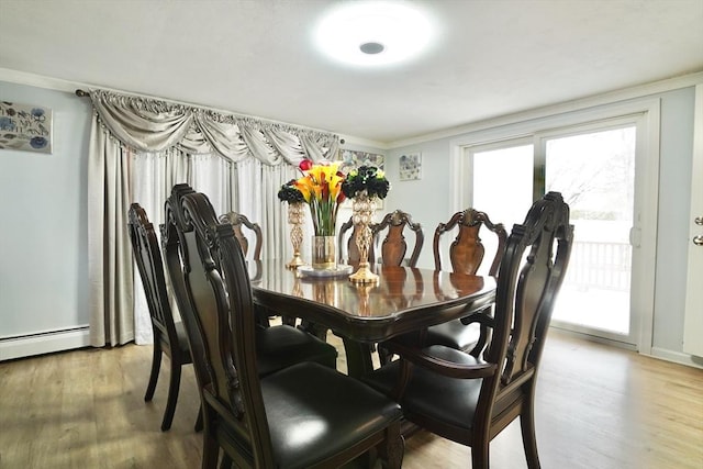 dining space featuring light wood-type flooring, ornamental molding, and a baseboard heating unit