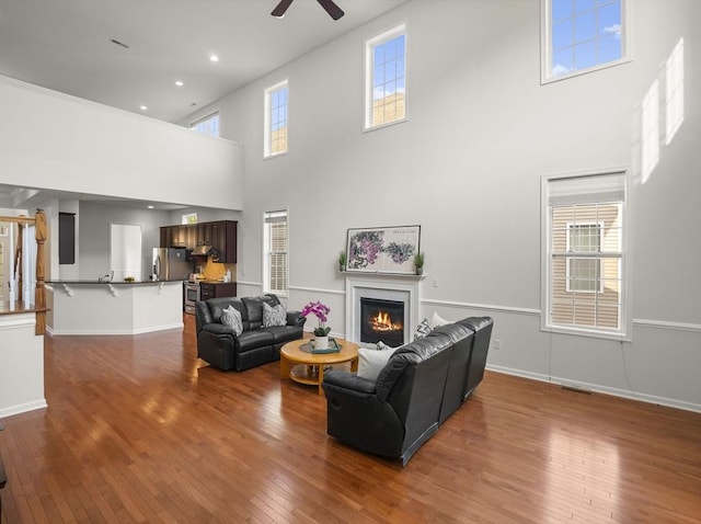 72 Sherwood Dr Unit 72, Methuen, MA 01844 - living area with a high ceiling, a ceiling fan, a glass covered fireplace, and wood-type flooring
