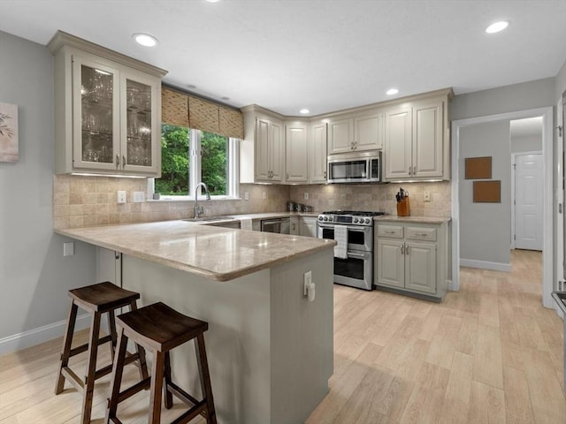 1 Benjamin Dr, Westborough, MA 01581 - kitchen featuring stainless steel appliances, a peninsula, a breakfast bar area, light wood-type flooring, and baseboards