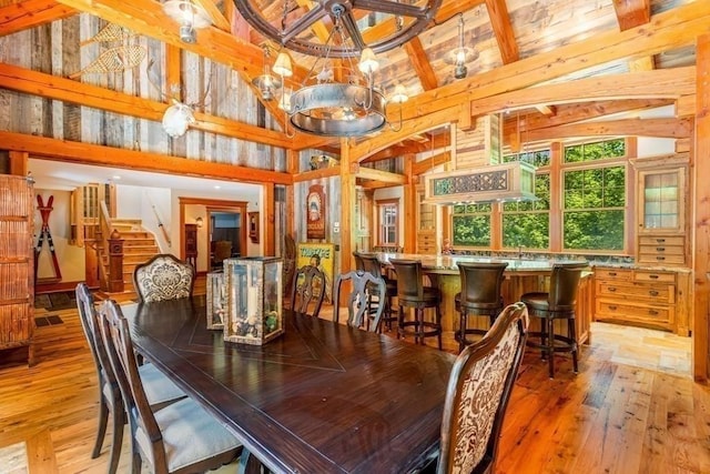 dining room with wood-type flooring, high vaulted ceiling, beamed ceiling, a chandelier, and wood walls