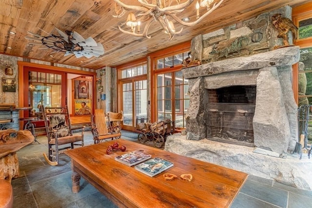 dining room with ceiling fan with notable chandelier, wood ceiling, a fireplace, and a wealth of natural light