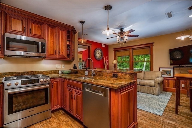 kitchen with kitchen peninsula, light wood-type flooring, stainless steel appliances, and sink