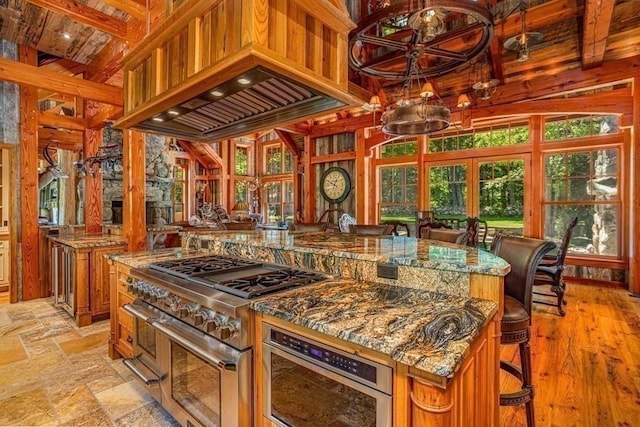 kitchen with french doors, stainless steel appliances, dark stone countertops, beamed ceiling, and a kitchen island