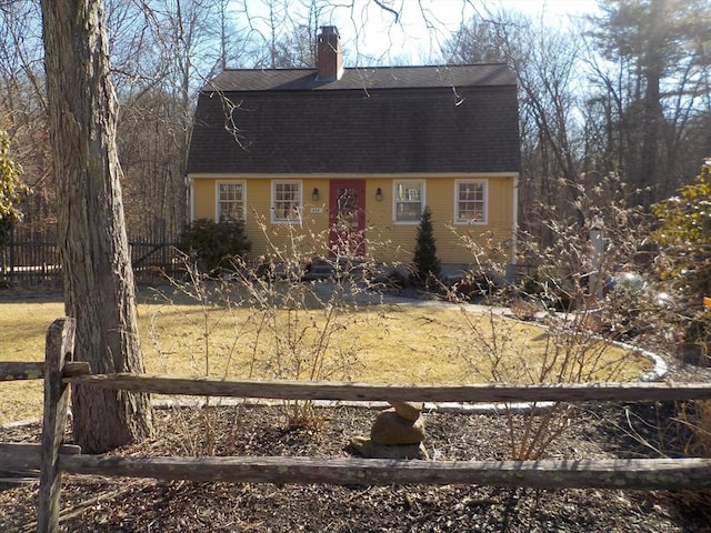 colonial inspired home featuring a shingled roof, a chimney, and fence