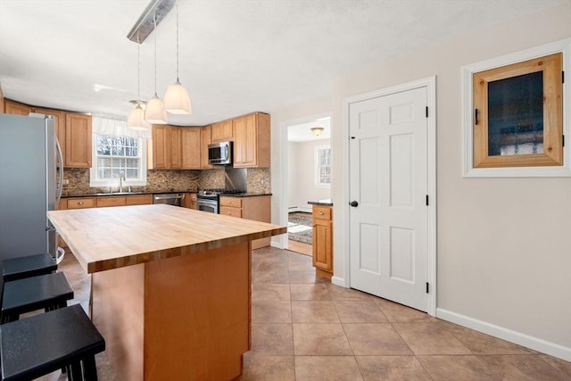 kitchen featuring backsplash, wooden counters, a breakfast bar, stainless steel appliances, and a sink