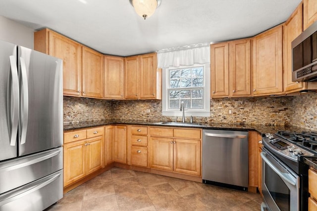 kitchen with dark stone countertops, backsplash, appliances with stainless steel finishes, and a sink