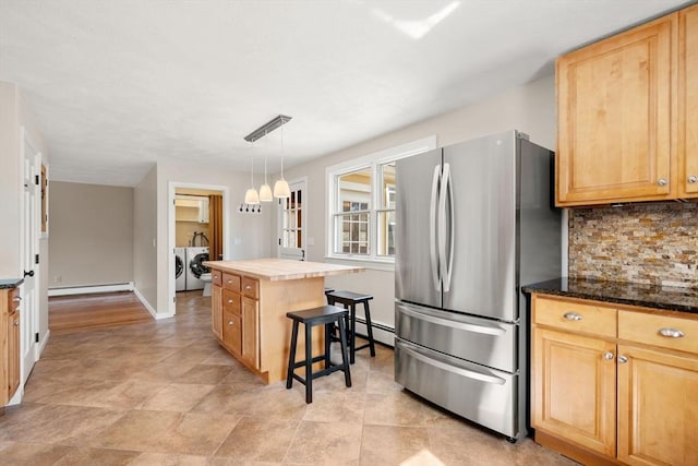 kitchen featuring tasteful backsplash, light brown cabinets, a baseboard heating unit, washer and clothes dryer, and freestanding refrigerator