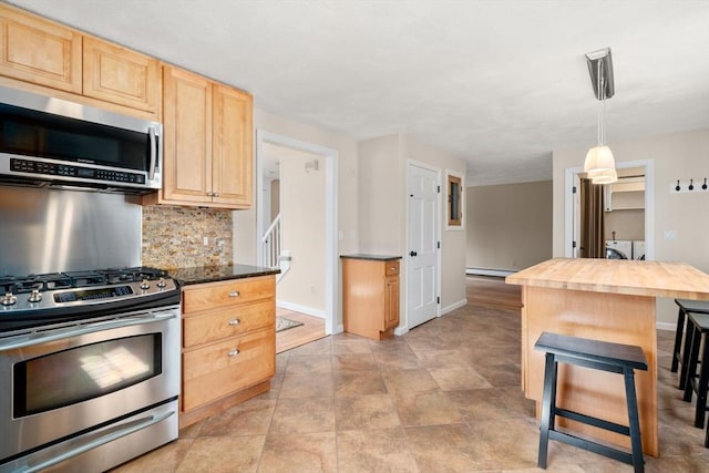 kitchen featuring a breakfast bar, light brown cabinetry, decorative backsplash, stainless steel appliances, and washer and dryer