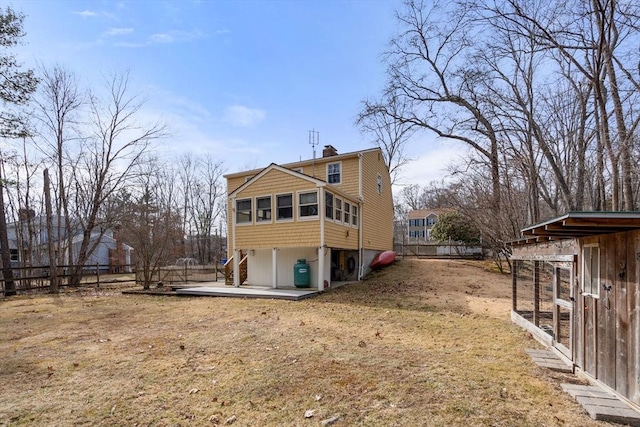 back of house with an outdoor structure, fence, and a chimney