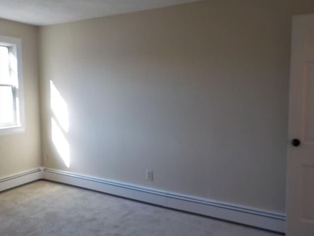 carpeted empty room with baseboard heating