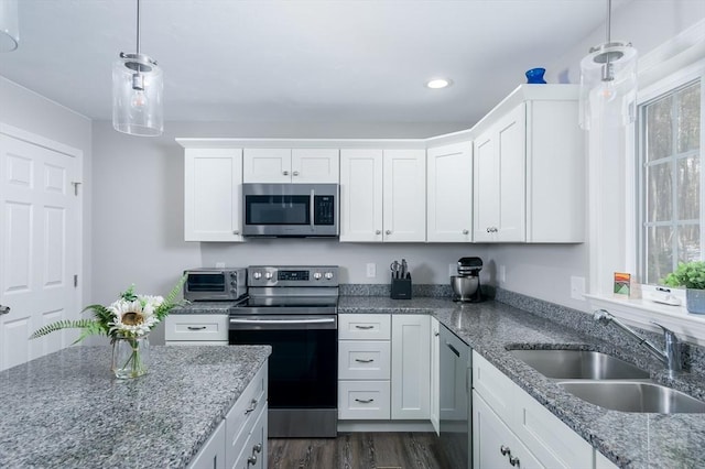 kitchen featuring pendant lighting, sink, stone counters, appliances with stainless steel finishes, and white cabinets