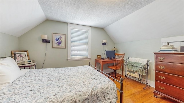 bedroom featuring vaulted ceiling, a textured ceiling, and light hardwood / wood-style floors