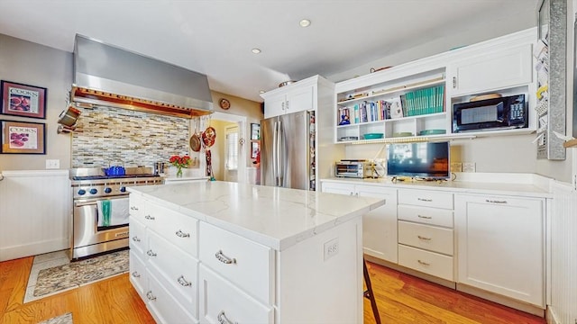 kitchen with white cabinetry, wall chimney exhaust hood, stainless steel appliances, and a center island