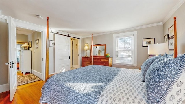 bedroom featuring ornamental molding, a barn door, and hardwood / wood-style floors