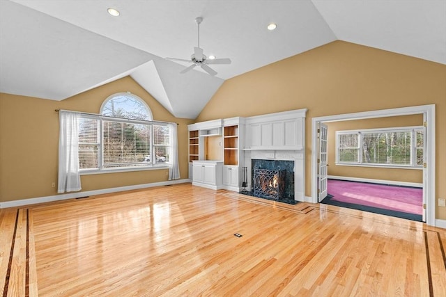 unfurnished living room with lofted ceiling, wood-type flooring, a premium fireplace, and ceiling fan