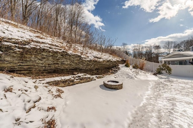 yard layered in snow featuring fence and a fire pit