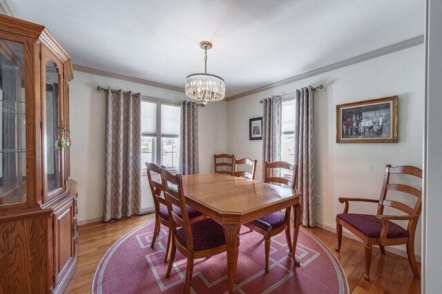 dining room featuring light wood-style flooring, a chandelier, and crown molding