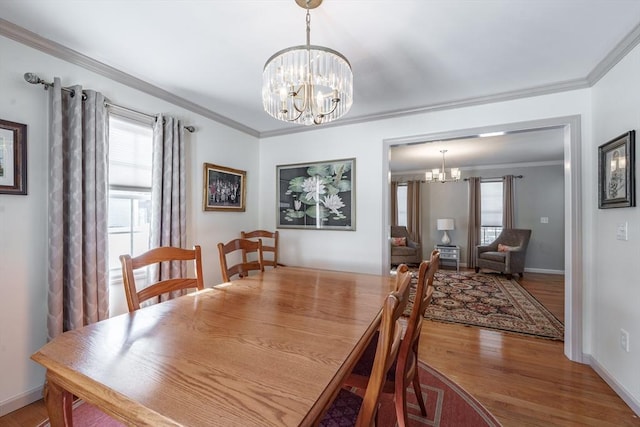 dining room featuring baseboards, ornamental molding, wood finished floors, and an inviting chandelier