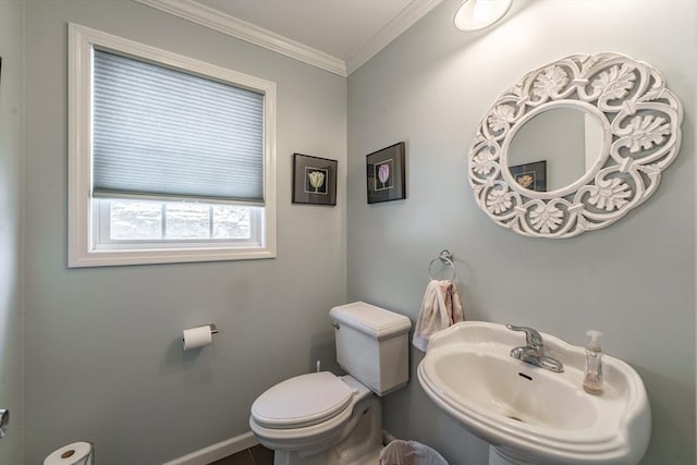 bathroom with toilet, crown molding, baseboards, and a sink