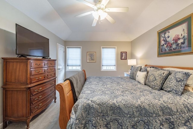 bedroom with a ceiling fan, a tray ceiling, and light colored carpet