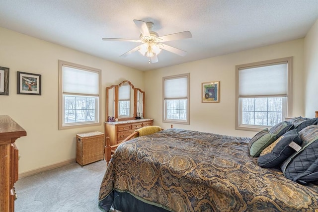 bedroom featuring light carpet, ceiling fan, multiple windows, and baseboards