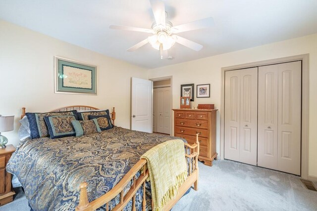 bedroom featuring ceiling fan, visible vents, a closet, and light colored carpet